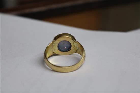 An engraved yellow metal and cabochon star sapphire ring, size O.